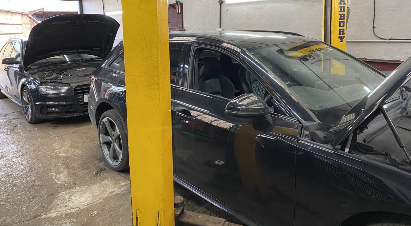 Two Audis with their bonnets up beside the yellow lift