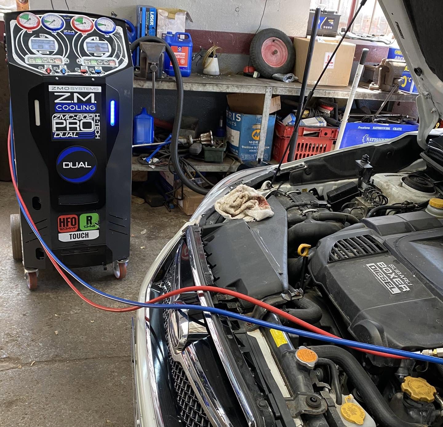 An engine bay connected to the workshop machine by red and blue hoses