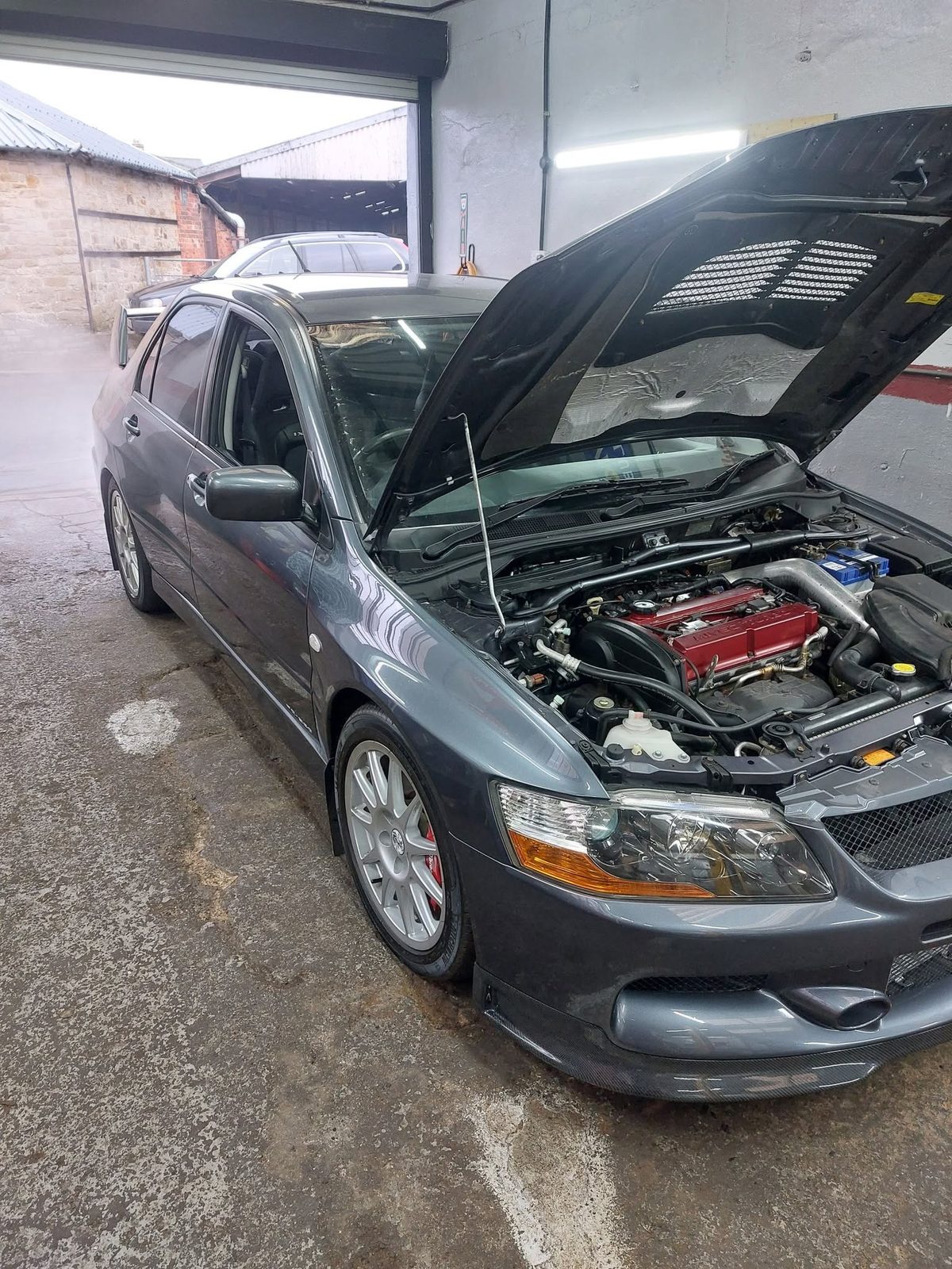 Grey Mitsubishi Lancer Evo with the bonnet up in the workshop
