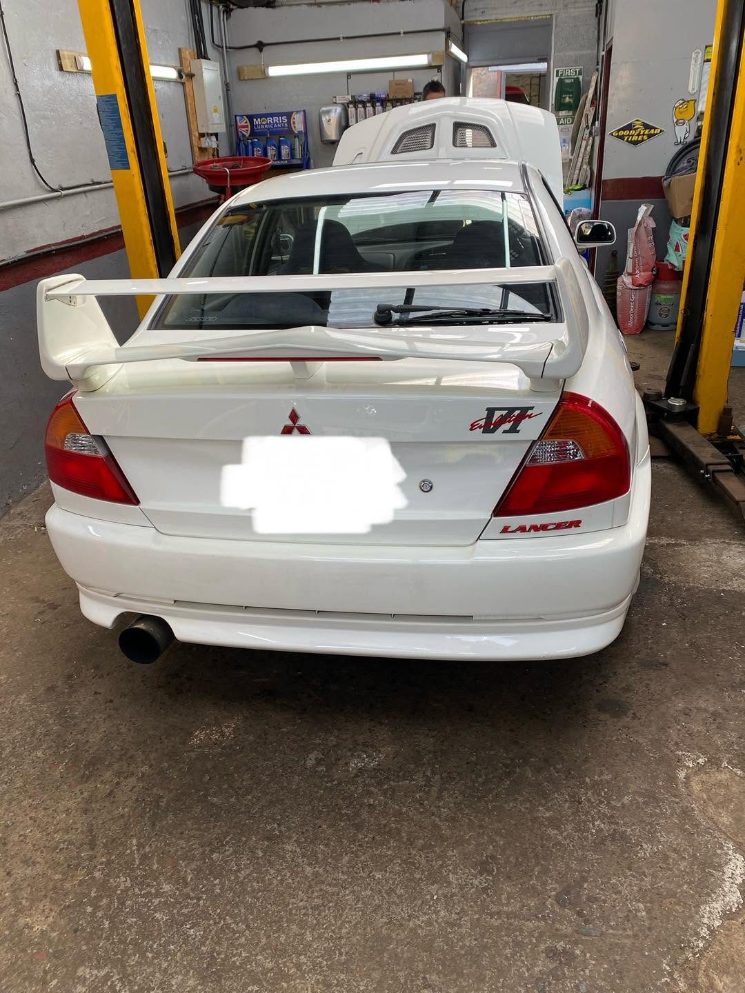 The white Lancer Evo from behind, with its rear wing