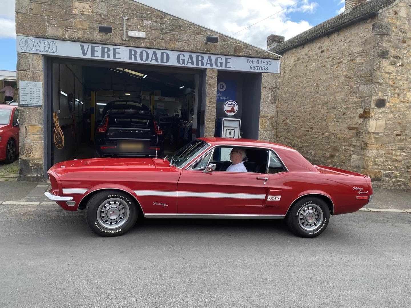 The red Mustang parked under the older grey Vere Road Garage sign