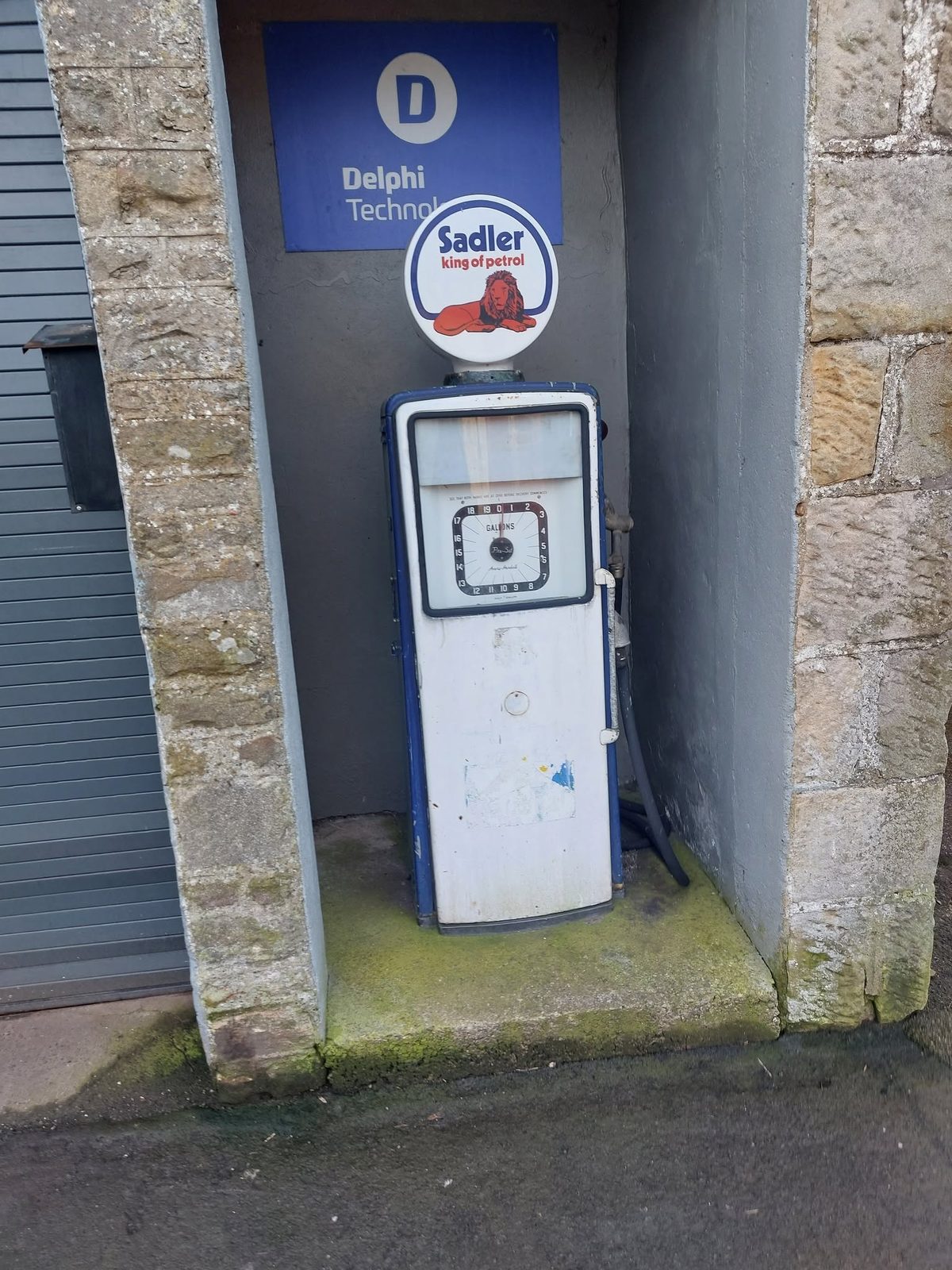 A vintage Sadler petrol pump standing in a stone recess by the door