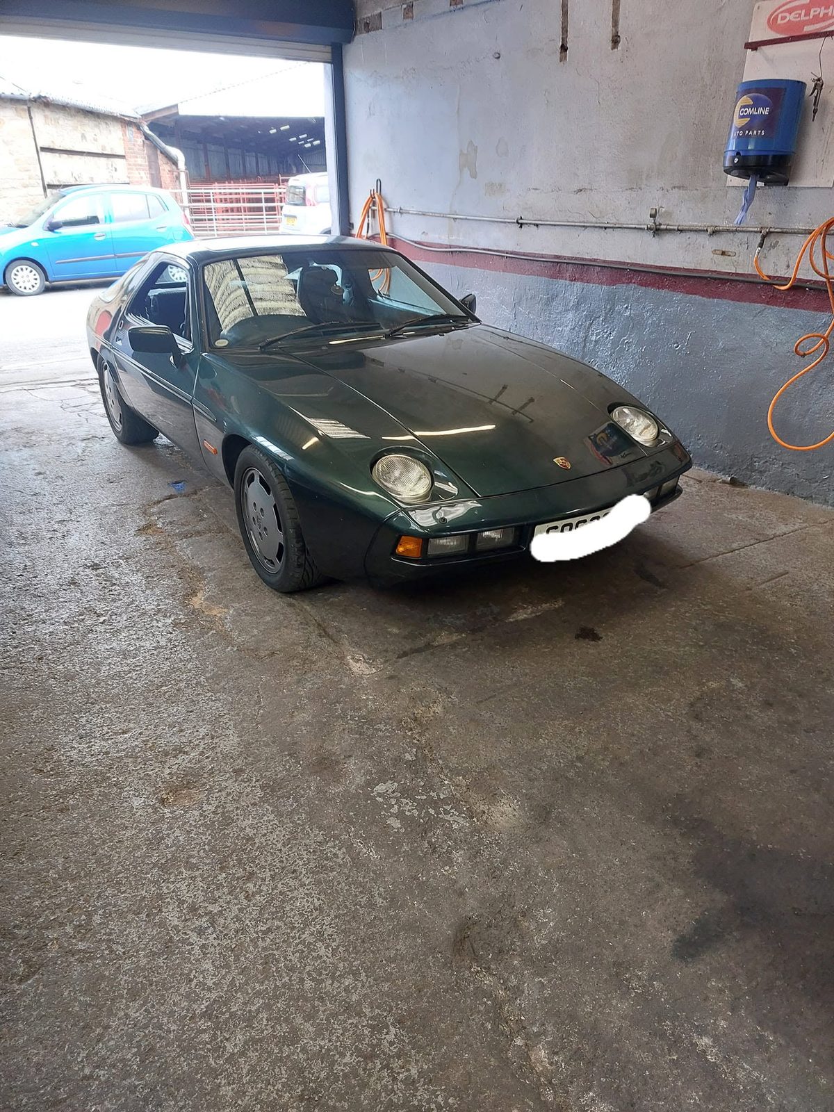 A dark green Porsche 928 in the workshop