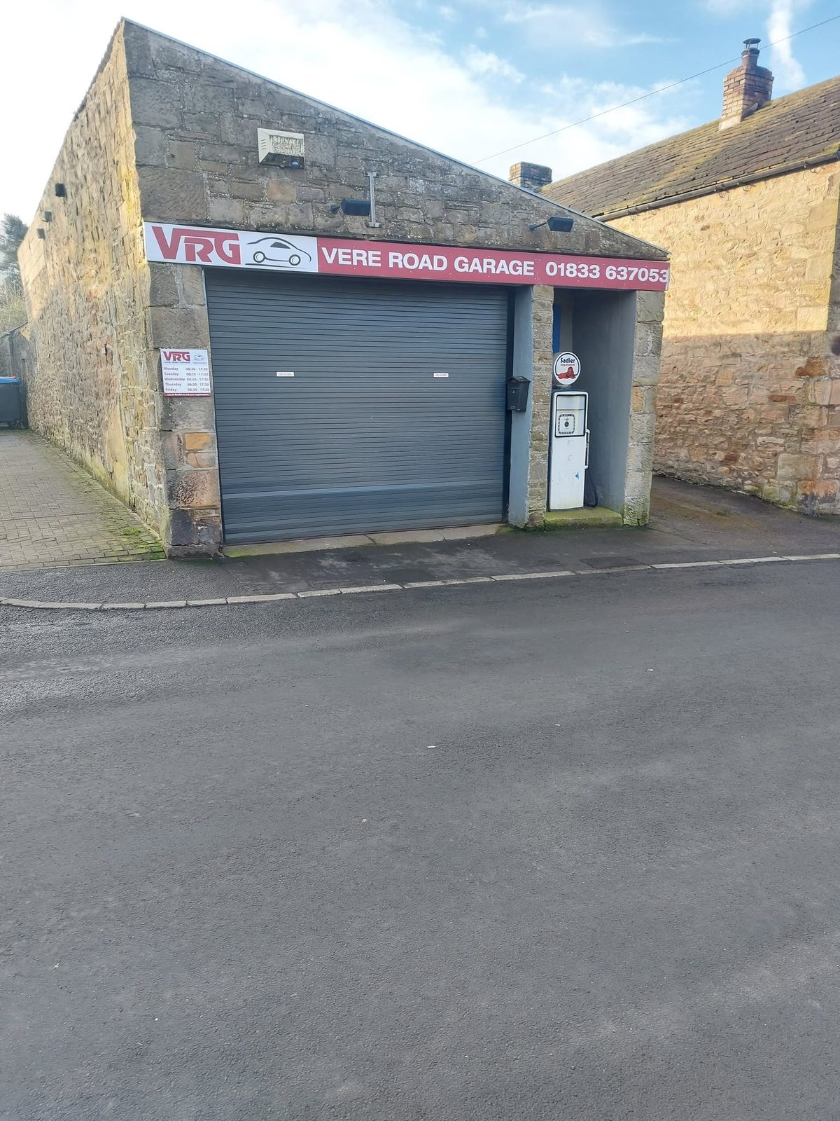 The stone-built workshop with its shutter down and the red sign above
