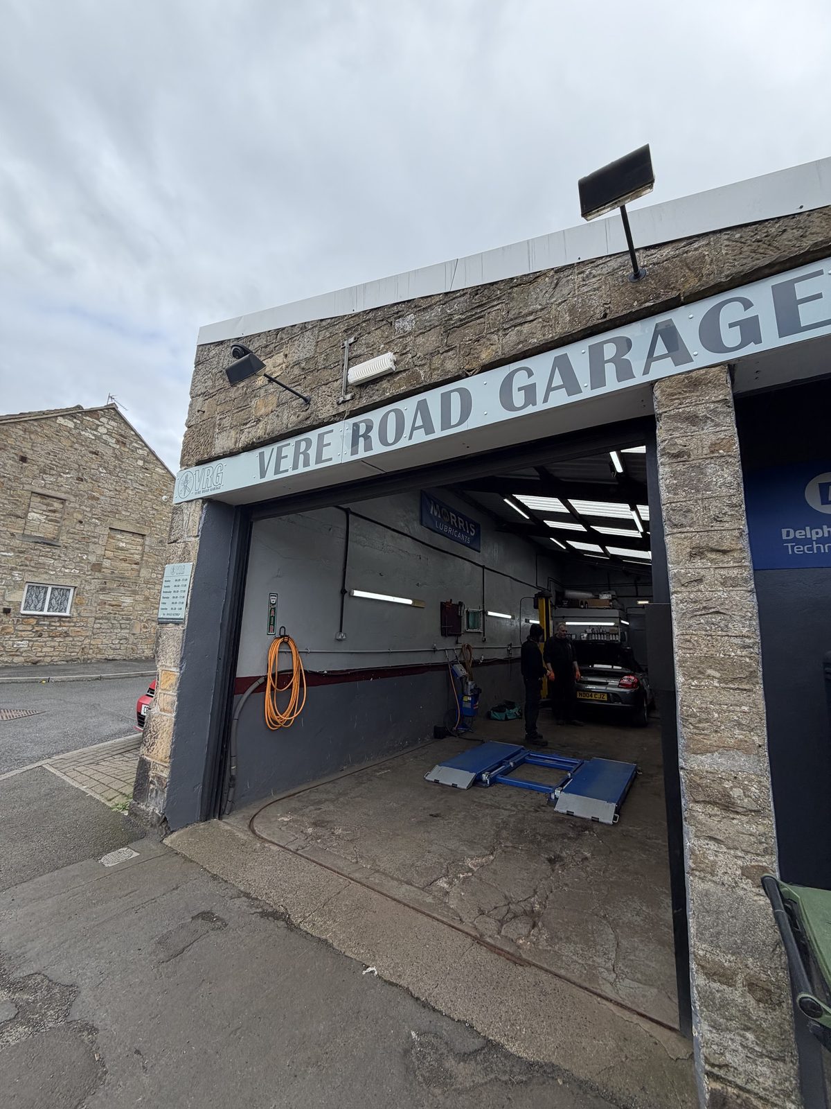The older grey Vere Road Garage sign over the open workshop bay